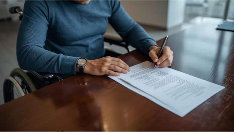 גבר אחרי תאונת עבודה חותם על מסמכים אצל עורך דין אובדן כושר עבודה עבור תביעת ביטוח